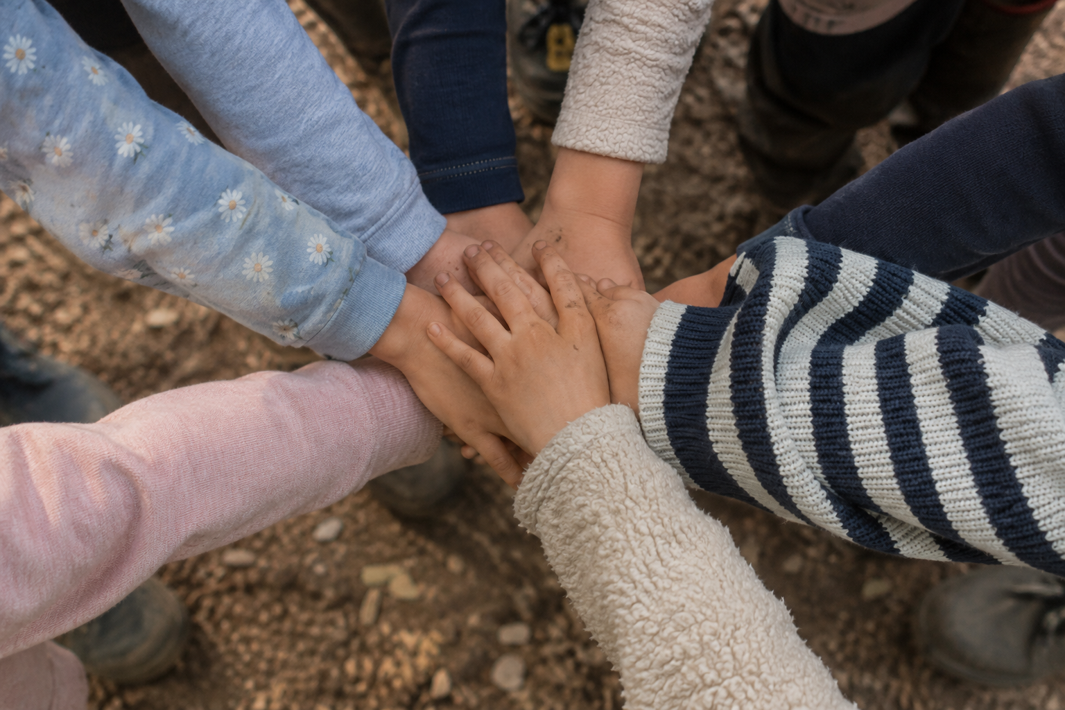 Kinderhände treffen sich in der Mitte eines Kreises — Freundschaften entstehen