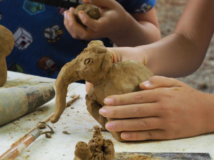 Kinderhände formen eine Elefantenfigur aus Ton in der Naturwerkstatt